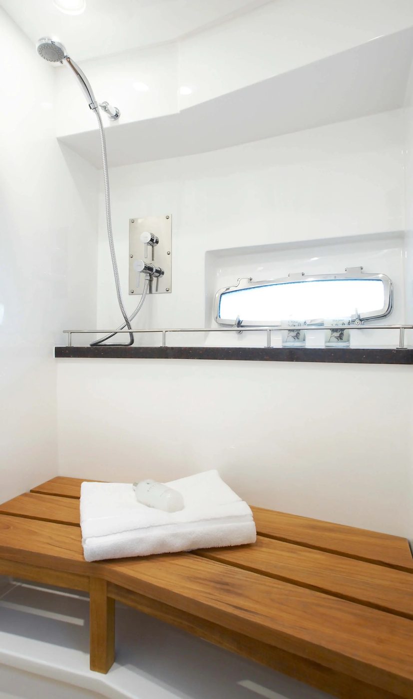 Separate shower with teak bench and fresh towels